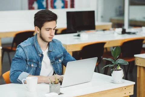 Serious young guy with beard working on laptop Stock Photos