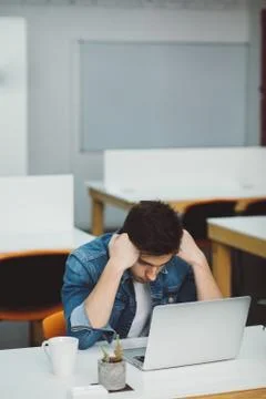 Serious young guy with beard working on laptop Stock Photos