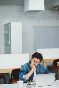 Serious young guy with beard working on laptop Stock Photos