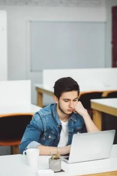 Serious young guy with beard working on laptop Stock Photos
