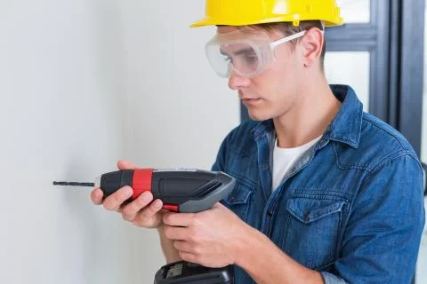 Serious young handyman using a drill Stock Photos