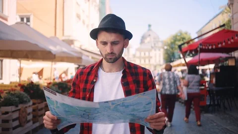 Serious young man holding a map looking at her looking around in the city center Stock Footage 92072166