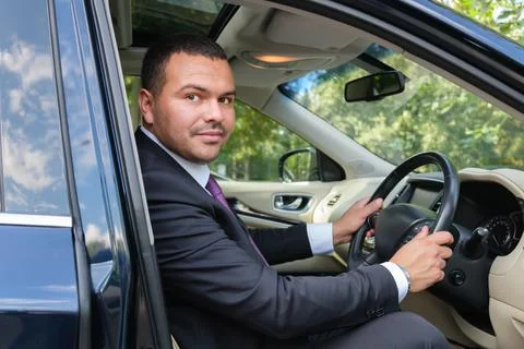 Serious young man of Middle Eastern appearance in a business suit is driving  Stock Photos
