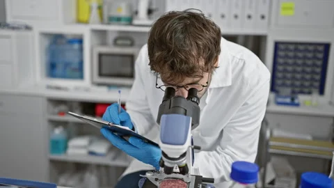 Serious young man scientist, a bearded blond, meticulously taking notes at .. Stock Footage 262760946