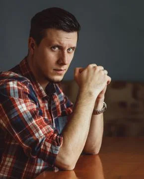 Serious young man sitting at the table Stock Photos