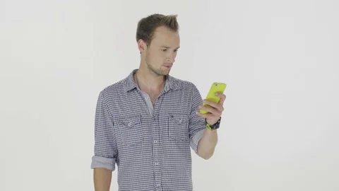 A serious young man is standing and using his cell phone. 스톡 동영상 80318614