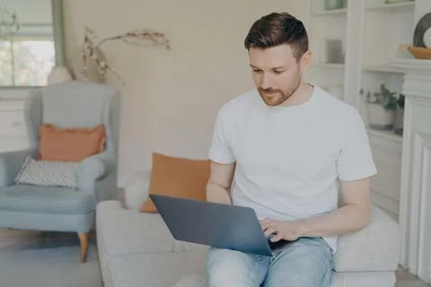 Serious young man using laptop computer for remote work from home Stock Photos