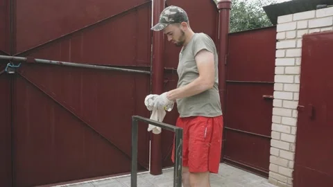 Serious young man in work uniform and gloves pours degreaser on a rag 库存影片 145395380