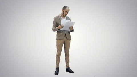 Serious young manager standing and reading documents on white background Stock Footage 73638682