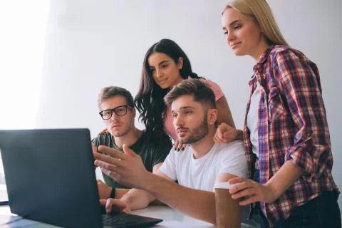 Serious young men sit at table and look at laptop screen. Brunette and blone Stock-Fotos