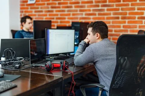 Serious young programmer sitting at his worktable inside the office 스톡 사진
