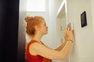 Serious Young Woman Setting Up The Alarm System Stock Photos