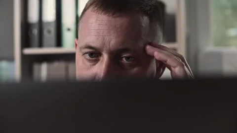 Seriously focused facial expression on a man working at a laptop Stock Footage 307597702