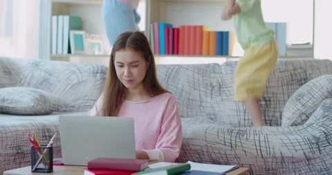Seriously Young mother while working at home with two daughters Stock Footage 138336936