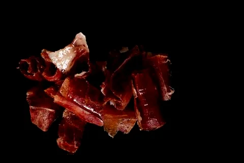 Serrano ham cut on black background. Stock Photos