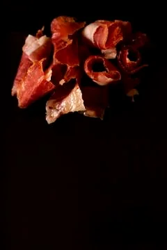 Serrano ham cut on black background. Stock Photos