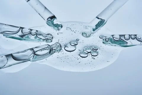 The serum flows from several pipettes into a single texture on a blue backg.. Foto stock