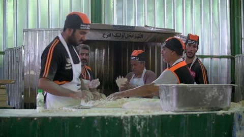 "Servants" knead dough to make bread for pilgrims during Arbaeen Pilgrimage Stock Footage 119245047