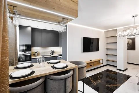 Served dining table with soft bar chairs in studio apartment Stock Photos