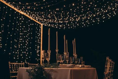 Served dinner table with candles and garlands. Stock Photos