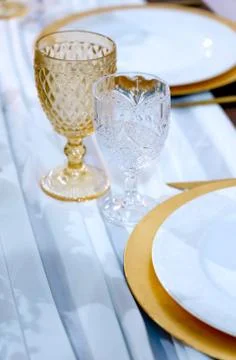 Served dinner table. Pair of vintage wineglasses and plates on white backdrop Stock Photos
