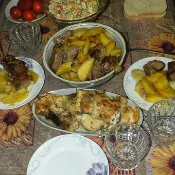 Served dinner table with roasted potatoes, meat, fish, and salads Stock Photos