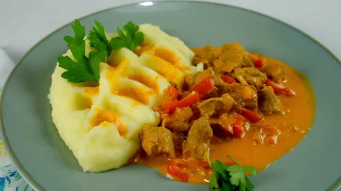 Served goulash and mashed potatoes with greenery on plate on kitchen at home. Stock Footage 312403421