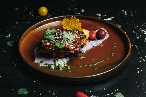 Served gourmet dish on rustic brown plate with vibrant garnishes and sauce Stock Photos
