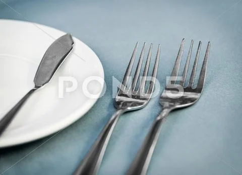 Served restaurant table with forks, white plate and knife Stock Photos