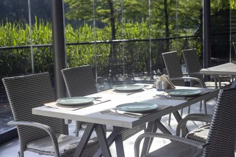 Served restaurant table on terrace with wicker chairs and scenic nature view Foto stock