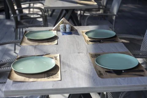 Served restaurant wooden table with light green plates and wicker chairs Foto stock