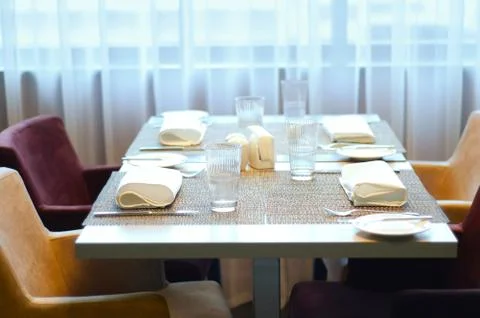 Served table and soft chairs in the cafe. Against the background of windows a Stock Photos