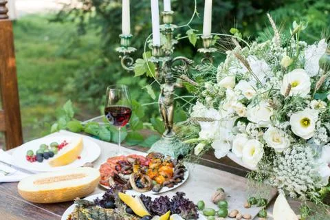 Served table with melon, grilled vegetables, glass of red wine and fruits Stock Photos