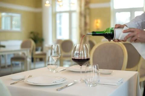 Served table restaurant wine being poured into glass, white tablecloth, plate Stock Photos