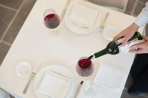Served table restaurant wine being poured into glass, white tablecloth, plate Stock Photos