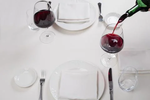 Served table restaurant wine being poured into glass, white tablecloth, plate Stock Photos