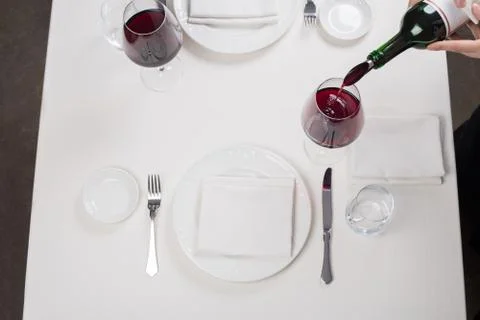 Served table restaurant wine being poured into glass, white tablecloth, plate Stock Photos