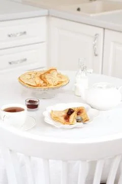 Served table with Thin pancakes with berries jam on glass stand with jam, bottle Foto stock