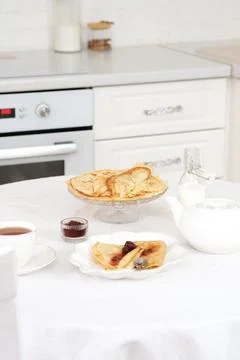 Served table with Thin pancakes with berries jam on glass stand with jam, bottle Stock Photos