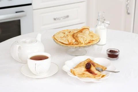 Served table with Thin pancakes with berries jam on glass stand with jam, bottle Stock Photos