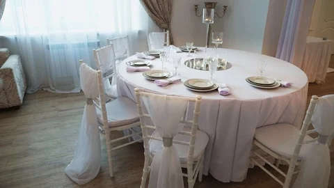 A served table with a white cloth on which there are plates and napkins Stock Footage 97716744