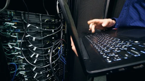 Server blocks and an IT support engineer operating a laptop near them Video stock 112174272