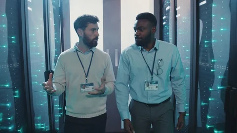 Server engineer talking with support technician walking along rack server Video stock 119081454