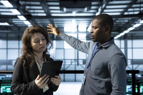 Server farm colleagues using device, adjusting cooling and power settings Stock Photos