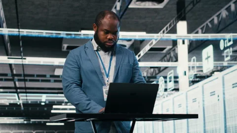 Server farm programmer at workplace desk using laptop to optimize electronics Video stock 330031576