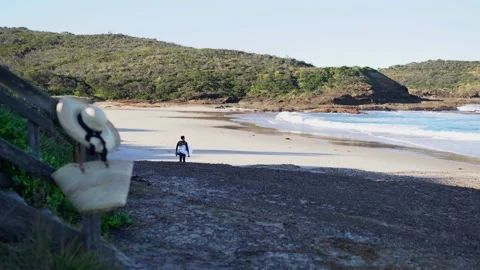 A server goes along a sandy beach. A straw hat and a bag hanging from stairs. Stockbeeldmateriaal 134654646