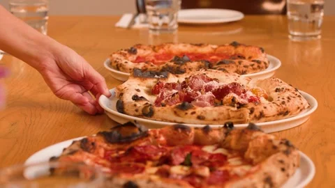 Server Hand Placing Fresh Neapolitan Pizza on Wooden Restaurant Table Stock Footage 337768940