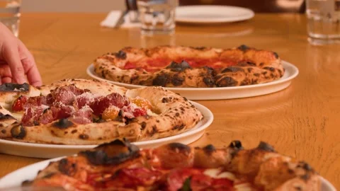 Server Placing Fresh Neapolitan Pizza with Prosciutto on Restaurant Table Stock Footage 337860402