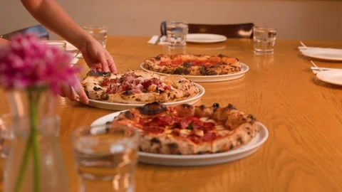 Server Placing Fresh Neapolitan Pizza on a Restaurant Table Stock Footage 337875712