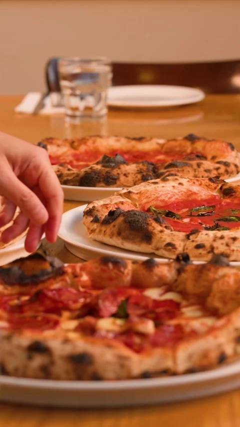 Server Placing Fresh Neapolitan Pizzas on a Wooden Restaurant Table Stock Footage 337767643